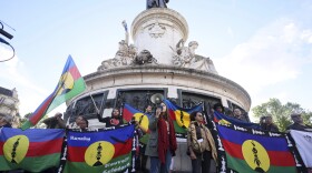 Demonstrators hold Kanak and Socialist National Liberation Front (FLNKS) flags during a gathering in Paris, Thursday May 16, 2024. Violence raged across New Caledonia for the third consecutive day Thursday, hours after France imposed a state of emergency in the French Pacific territory, boosting security forces' powers to quell unrest in the archipelago that has long sought independence. (AP Photo/Thomas Padilla)