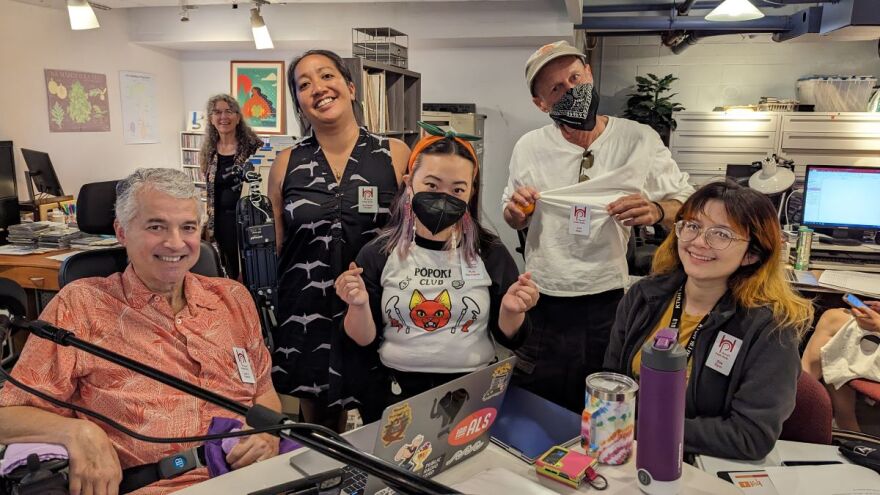 Foreground, from left: President and General Manager José A. Fajardo, General Assignment Reporter Ku‘uwehi Hiraishi, Administrative Assistant Mia Yoshimoto, Blues from the Basement and B-Sides and Beyond host Jon Alan, News Producer Zoe Dym. Background: Kanikapila Sunday host Louise Keali‘iloma King Lanzilotti.