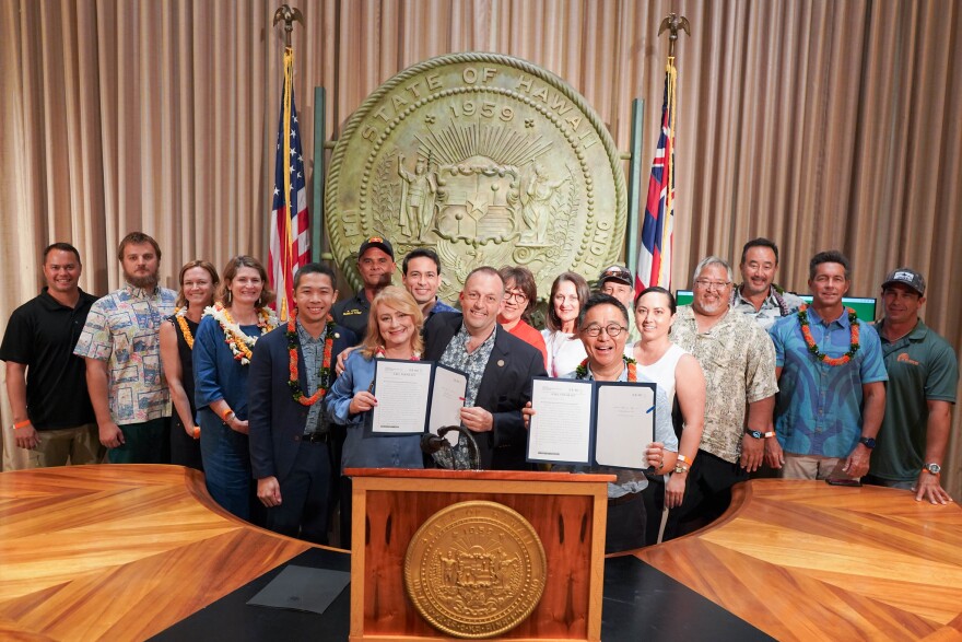 Gov. Josh Green is joined by other lawmakers and water safety advocates at a press conference on May 15, 2024. Green signed into law a bill that would authorize the sale of Duke Kahanamoku Hawaiʻi license plates. Money from the license plates would fund the promotion of water safety. A second bill marks May 15 as Water Safety Day in Hawaiʻi.