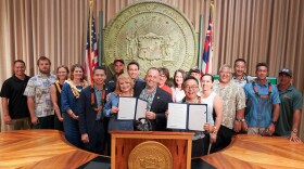 Gov. Josh Green is joined by other lawmakers and water safety advocates at a press conference on May 15, 2024. Green signed into law a bill that would authorize the sale of Duke Kahanamoku Hawaiʻi license plates. Money from the license plates would fund the promotion of water safety. A second bill marks May 15 as Water Safety Day in Hawaiʻi.