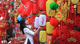 A woman looks at lanterns at the traditional Lunar New Year "Tet" market in the old quarter of Hanoi, Vietnam, Friday, Jan. 28, 2022. (AP Photo/Hau Dinh)