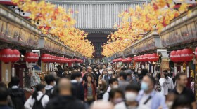 FILE - Tourists walk through a promenade lined with souvenir shops leading to the Sensoji Buddhism temple in the famed Asakusa district of Tokyo. (AP Photo/Hiro Komae, File)