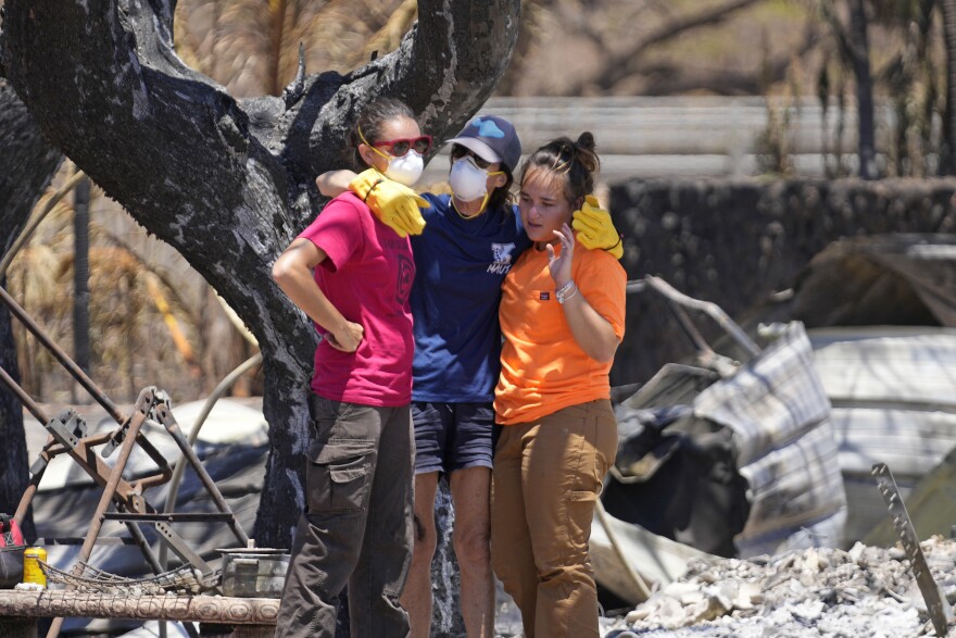 Women hug after digging through rubble of a home destroyed by a wildfire on Friday, Aug. 11, 2023, in Lāhainā, Hawaiʻi. (AP Photo/Rick Bowmer)