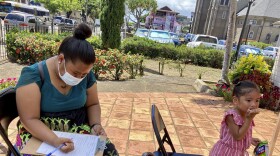 Shersina Roby fills out a form to get her second dose of the COVID-19 vaccine dose while 3-year-old Gezelle Fanny has a snack at a vaccination clinic in Honolulu, July 14, 2021. (AP Photo/Jennifer Since Kelleher)