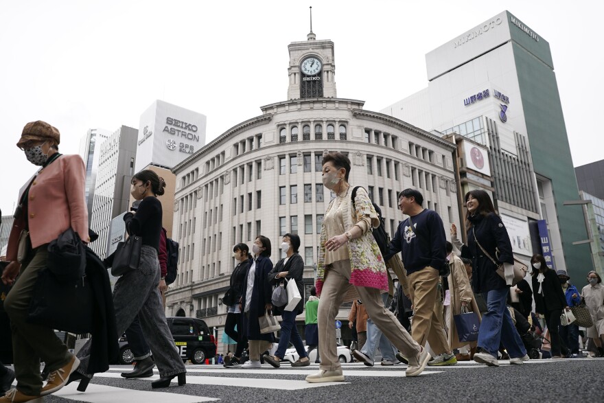 FILE - People walk across a pedestrian crossing in Ginza shopping district on March 31, 2023, in Tokyo.