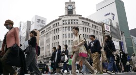 FILE - People walk across a pedestrian crossing in Ginza shopping district on March 31, 2023, in Tokyo.