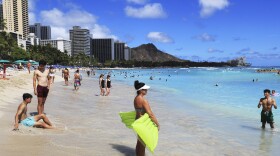 FILE - People take to the waves on Waikīkī Beach on June 23, 2022. (AP Photo/Marco Garcia)