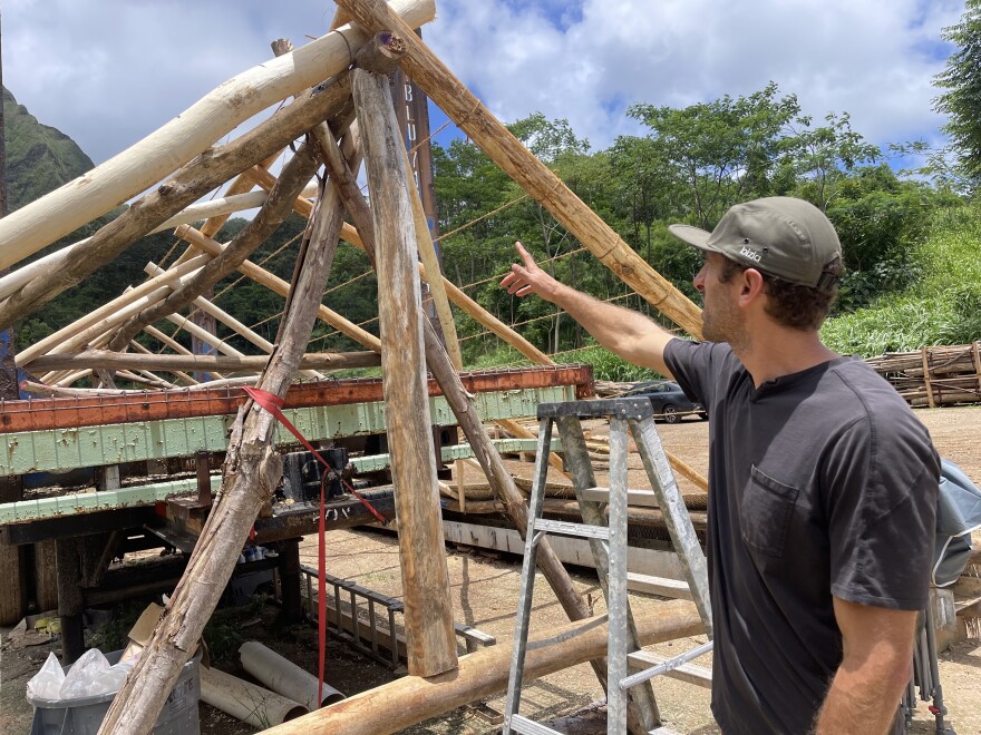 Joey Valenti of the Albizia Project points to the wood used for the last hale buildout.