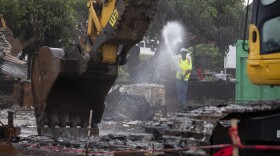 A worker sprays water on fire debris in Lahaina on Jan. 17, 2024.