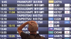 A foreign traveler stands in front of a flight information board upon his arrival at the Haneda International Airport Tuesday, Oct. 11, 2022, in Tokyo. Japan's strict border restrictions are eased, allowing tourists to easily enter for the first time since the start of the COVID-19 pandemic. Independent tourists are again welcomed, not just those traveling with authorized groups. (AP Photo/Eugene Hoshiko)