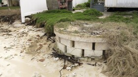 FILE -- This Jan. 26, 2015 photo provided by the Hawaiʻi Department of Land and Natural Resources shows a partially exposed cinderblock cesspool pit with a lid on a badly eroding shoreline in Punaluʻu, Hawaiʻi.