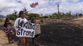 Children hold signs and a Hawaiian flag in Lāhainā, Hawaiʻi, Monday, Aug. 21, 2023.