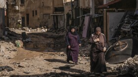 Palestinian women walk past an area damaged after an Israeli military raid in Jenin refugee camp in the West Bank, Friday, Nov. 10, 2023. (AP Photo/Majdi Mohammed)