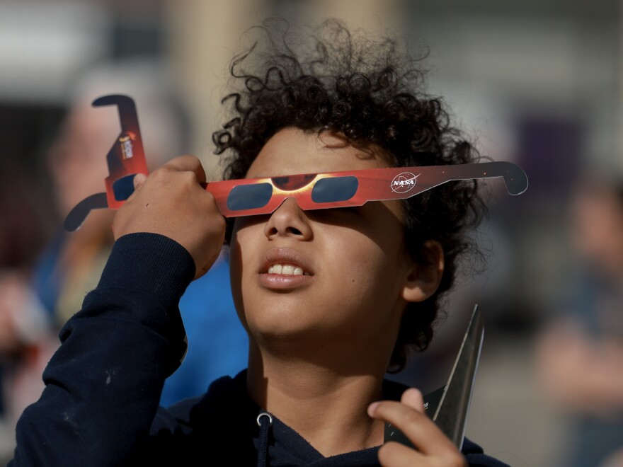 Junior Espejo looks through eclipse glasses being handed out by NASA in Houlton, Maine. Used correctly, eclipse glasses prevent eye damage.