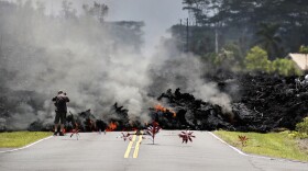 FILE - In this May 5, 2018 photo, a man photographs lava from Kīlauea volcano as it flows through the Leilani Estates subdivision near Pāhoa, Hawaiʻi.