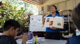 Sacred Hearts School teacher Charlene Ako shows a picture of the princess with a lei of bird feathers in connection with third graders from Princess Nāhiʻenaʻena Elementary at her class at Sacred Hearts Mission Church on Tuesday, Oct. 3, 2023. (AP Photo/Mengshin Lin)