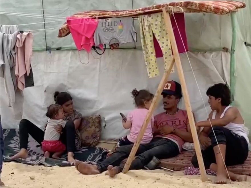 Displaced Palestinians in Rafah sit in the shade of their tent on a 100-degree day in the Gaza Strip.