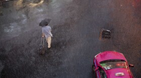 FILE - A man braves through rain on a road during a downpour in Bangkok, Thailand, Thursday, Aug 22, 2019. (AP Photo/Gemunu Amarasinghe)