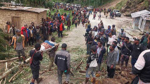 In this photo provided by the International Organization for Migration, an injured person is carried on a stretcher to seek medical assistance after a landslide in Yambali village, Papua New Guinea, Friday, May 24, 2024. More than 100 people are believed to have been killed in the landslide that buried a village and an emergency response is underway, officials said. 