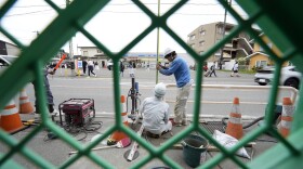 Workers set up a barricade near the Lawson convenience store, background, Tuesday, April 30, 2024, at Fujikawaguchiko town, Yamanashi Prefecture, central Japan. (AP Photo/Eugene Hoshiko)