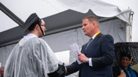 Robert Hale (right) gives an envelope with cash to a graduating UMass Dartmouth student at last week's commencement. Each of the 1,200 graduates received $1,000 onstage, half to keep and half to donate.