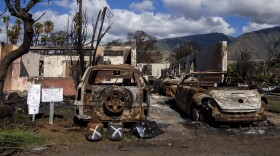 Burned cars and propane tanks with markings on them sit outside a house destroyed by wildfire, Friday, Dec. 8, 2023, in Lahaina, Hawaiʻi. (AP Photo/Lindsey Wasson)