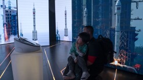 A child looks at displays showing the launch of Chinese space rockets during an exhibition about China's space program in Beijing, Thursday, Dec. 28, 2023.