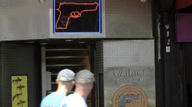 FILE - People walk past a gun club in Honolulu, June, 23, 2022. Honolulu is agreeing to approve or deny applications to carry concealed guns within four months in response to a lawsuit by residents who faced delays of more than a year.