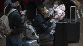 A child sits on a suitcase at Beijing West Railway Station in Beijing, Wednesday, Jan. 18, 2023. China in December lifted its strict "zero-COVID" policy, letting loose a wave of pent-up travel desire, particularly around China's most important time for family gatherings, referred to in China as the Spring Festival, that may be the only time in the year when urban workers return to their hometowns.