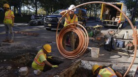 FILE - Workers prepare to replace older water pipes with a new copper one in Newark, N.J., Oct. 21, 2021.