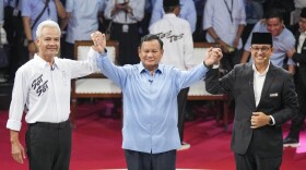 FILE - Presidential candidates, from left, Ganjar Pranowo, Prabowo Subianto and Anies Baswedan holds hands as they pose for photographers after the first presidential candidates' debate in Jakarta, Indonesia, Tuesday, Dec. 12, 2023. Indonesia, the world's third-largest democracy, will open its polls on Wednesday to nearly 205 million eligible voters in presidential and legislative elections, the fifth since Southeast Asia's largest economy began democratic reforms in 1998. (AP Photo/Tatan Syuflana, File)