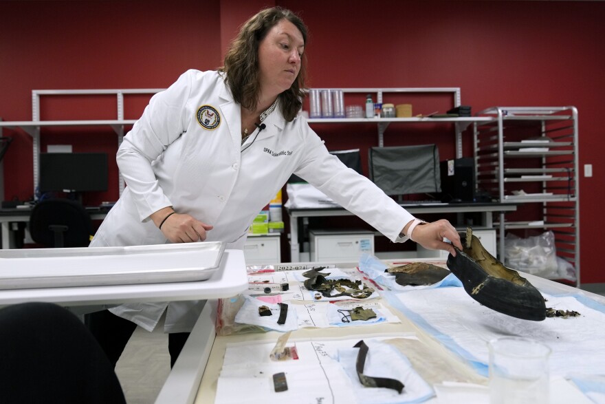 Defense POW/MIA Accounting Agency forensic anthropologist Carrie Brown looks at objects in a lab at Offutt Air Force Base, Monday, May 20, 2024, in Bellevue, Neb. Generations of American families have grown up without ever knowing exactly what happened to their loved ones who served in the military. But a lab tucked away above the bowling alley on Offutt Air Force Base in the Omaha suburbs and a sister lab in Hawaii that are part of the federal DPAA are steadily answering those lingering questions and offering about 200 families a year the chance to honor their relatives with a proper burial. (AP Photo/Charlie Neibergall)